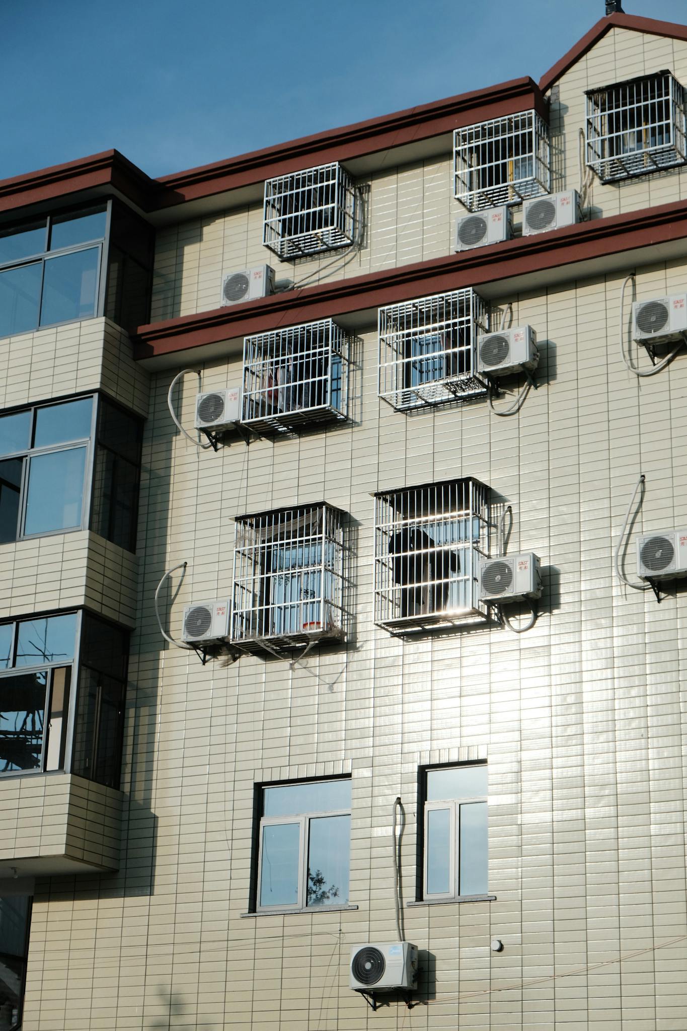 Exterior of a building with multiple air conditioners and window cages.